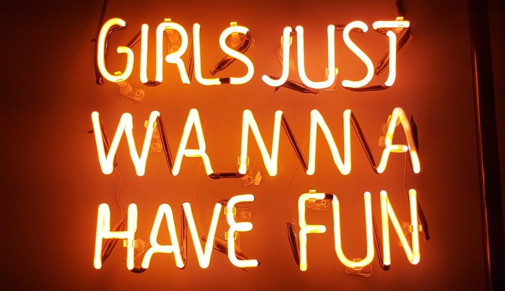 Neon sign with pink lights displaying the phrase 'girl just wanna have fun'.